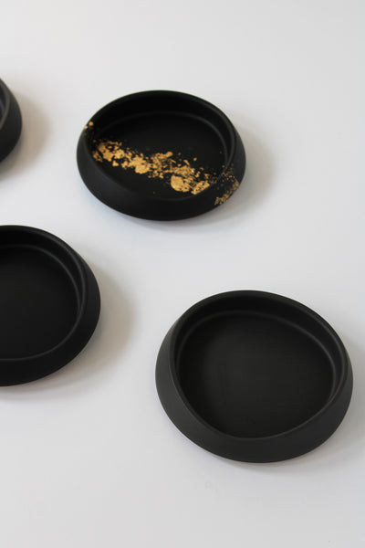 Black stone effect coasters with gold accents on a white background
