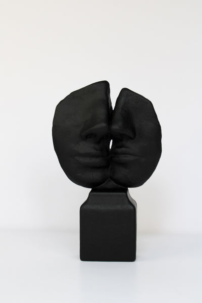 Abstract black face sculpture with stone-like texture


